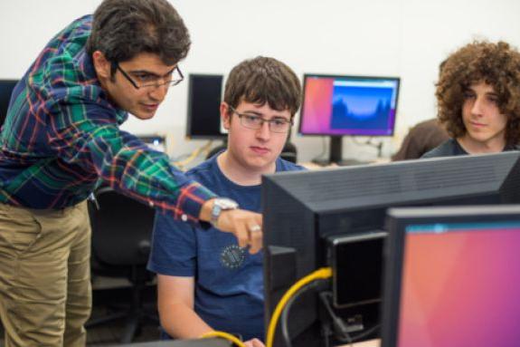 Professor working with students on computer 