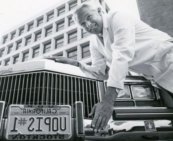 man with car with license plate that reads "uopis#1"